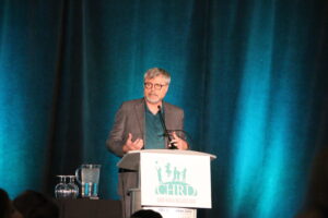 Terry Klassen speaking on stage at CHRD.