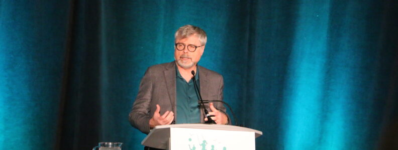 Terry Klassen speaking on stage at CHRD.