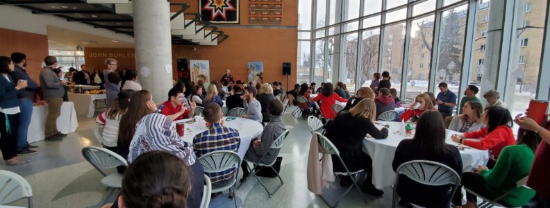 Large group of people mingle on the ground floor of the John Buhler Research Centre.