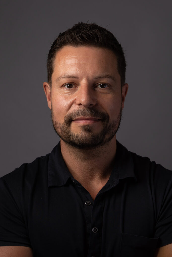 Portrait of Dr Tremblay in a black collared shirt with dramatic lighting.